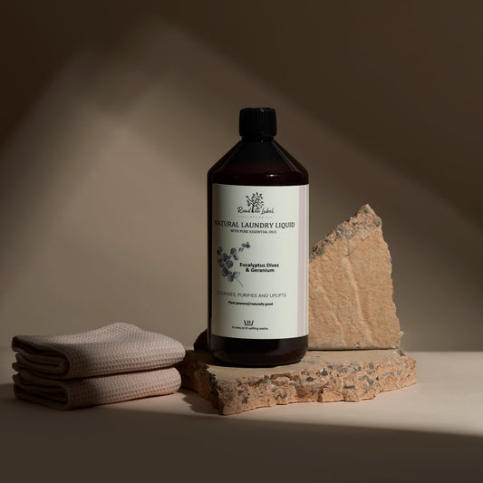 Bottle of natural laundry liquid with a label, folded towel, and stone on a neutral background