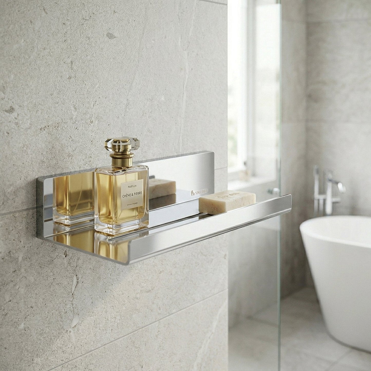 Smedbo Sideline DK5001 Polished Stainless Steel Shower Shelf on Limestone Wall Tiles — Styled with Chêne & Pierre Perfume Bottle and Natural Soap Bar, Freestanding Bath in Background