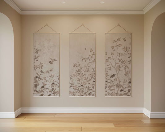 Three floral wall hangings on a beige wall with wooden flooring.