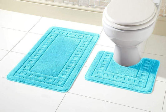 Turquoise bath mat set in front of a toilet on a tiled bathroom floor.