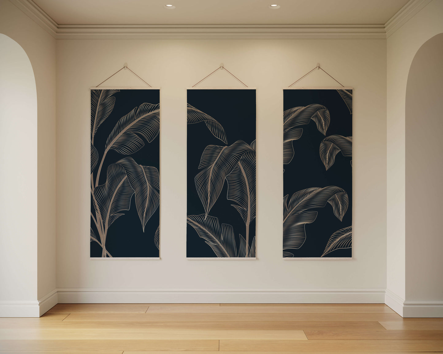 Three vertical wall art pieces with leaf patterns hanging on a beige wall.