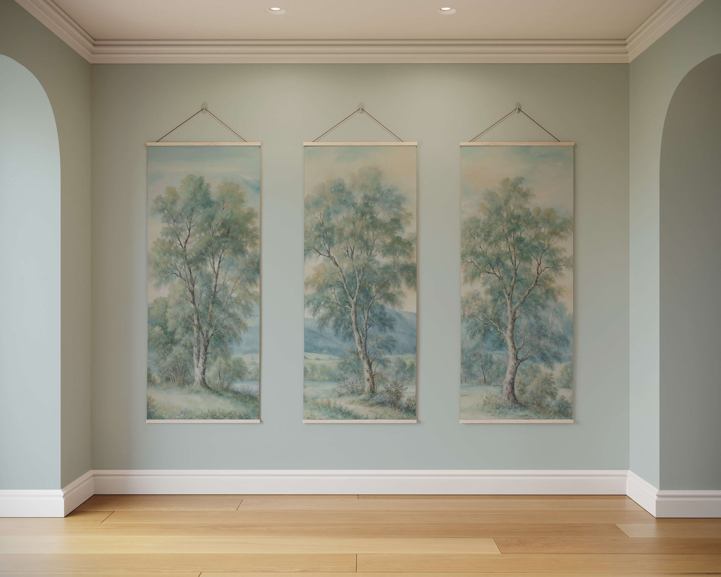 Three tree paintings hanging on a wall in a room with wooden flooring.