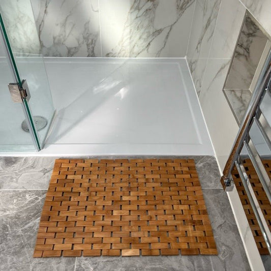 Bamboo bath mat on grey tiled floor in a modern bathroom