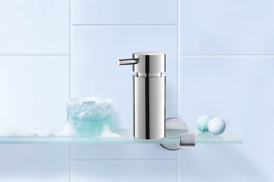 polished steel soap dispenser on glass shelf in a modern bathroom setting