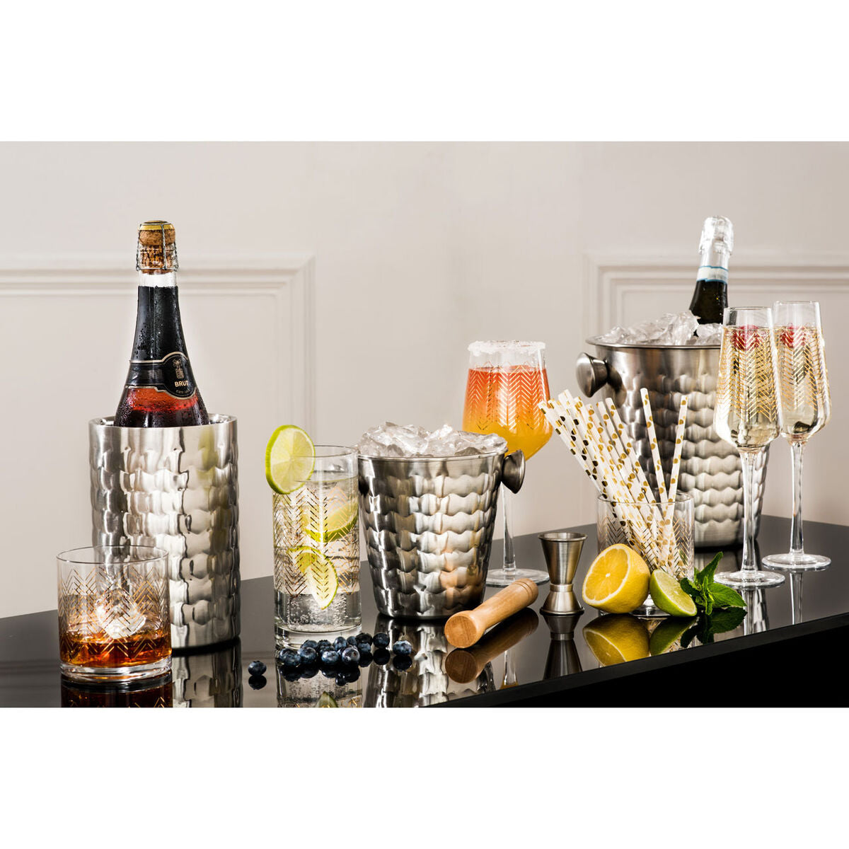 Alcohol bottles, glasses, and mixers on a reflective surface with a neutral background