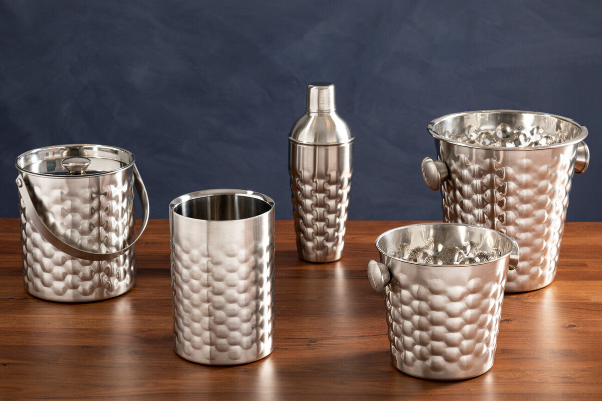 Set of silver cocktail shakers and ice buckets on a wooden surface with a dark blue background