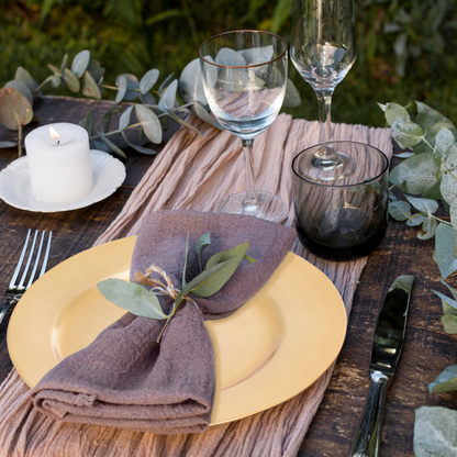 Gold charger plate styled with glassware and cutlery on a dining table