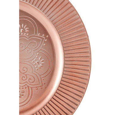 Rose gold charger plate laid beneath a dinner plate in a place setting