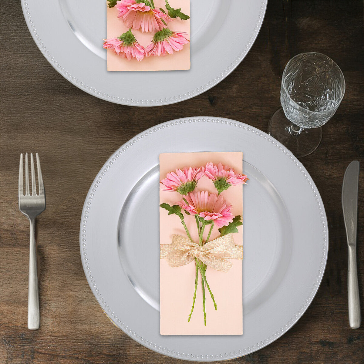 Silver charger plate styled with tableware for a formal dinner