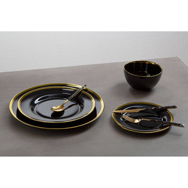 Black glass charger plate laid beneath a dinner plate in a table setting