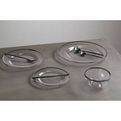 Glass charger plate laid beneath a dinner plate in a place setting