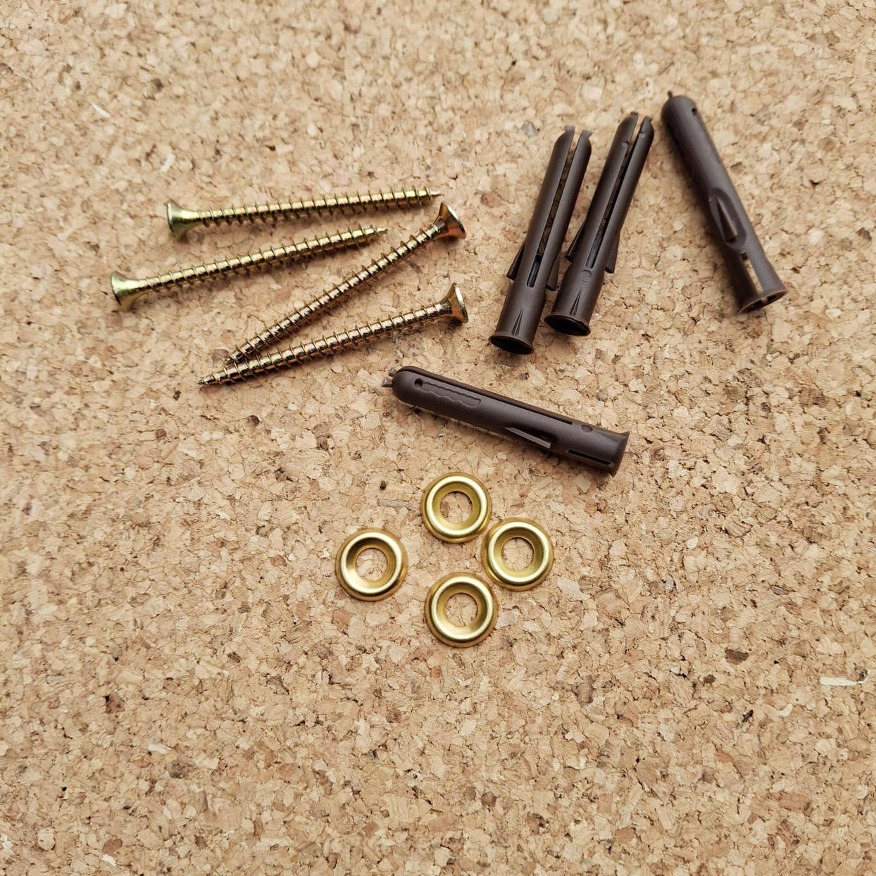 Nails, screws, and metal eyelets on a cork background