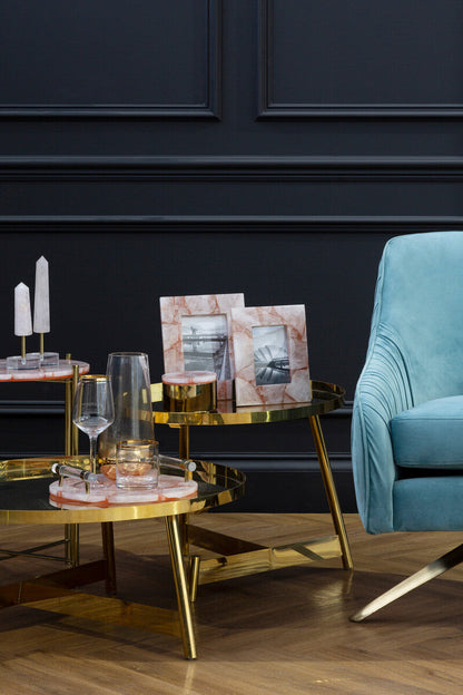 Modern living room with a blue armchair, gold coffee table, and dark paneled walls.