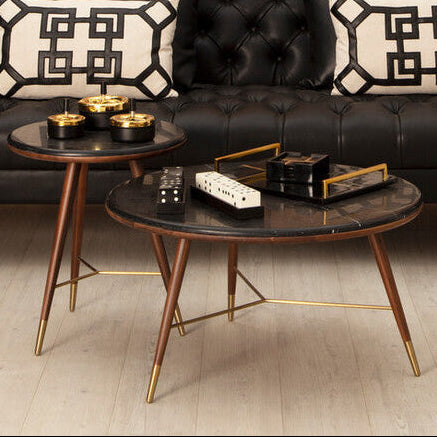 Round coffee table with gold legs in a living room setting