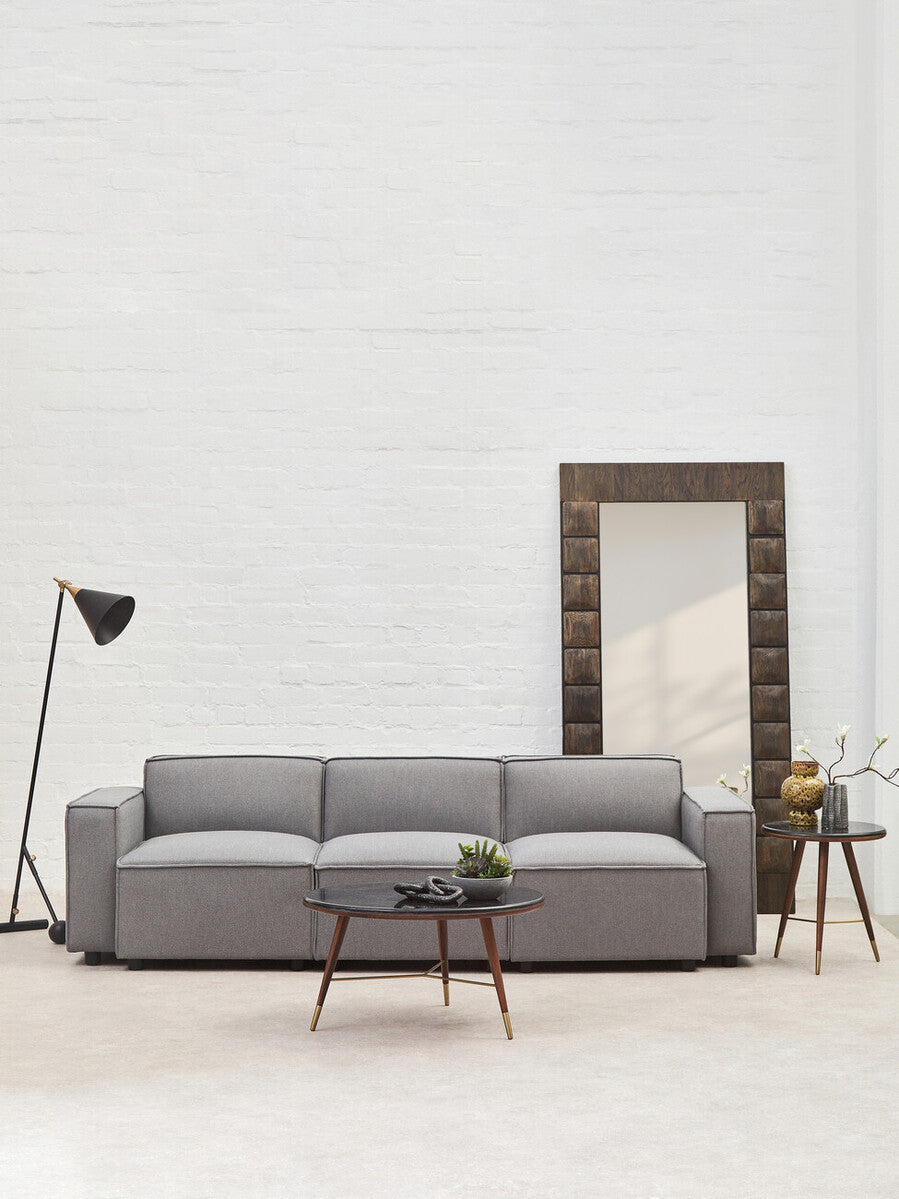 Gray sofa in a modern living room with a mirror and lamp.