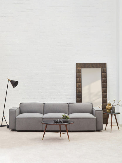 Gray sofa in a modern living room with a mirror and lamp.