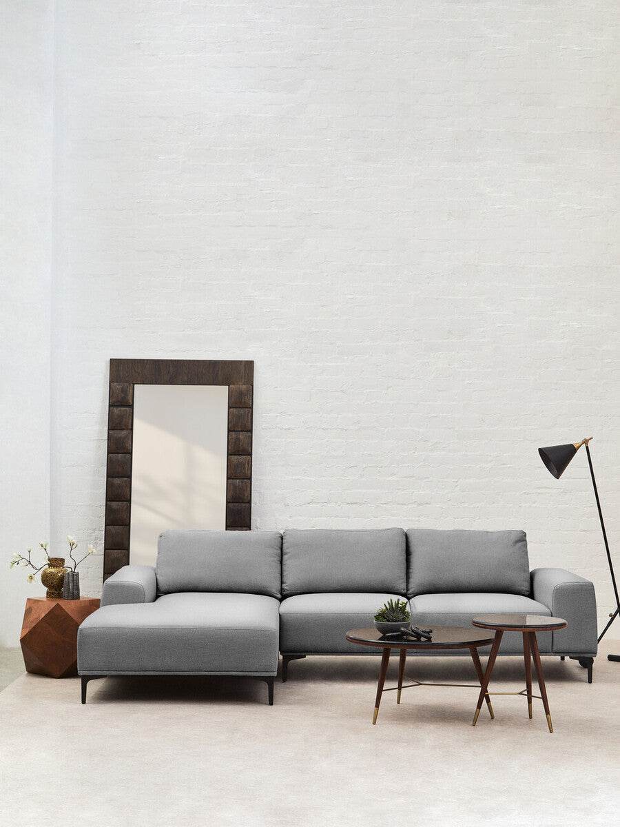 Gray sectional sofa in a modern living room with a mirror and lamp.