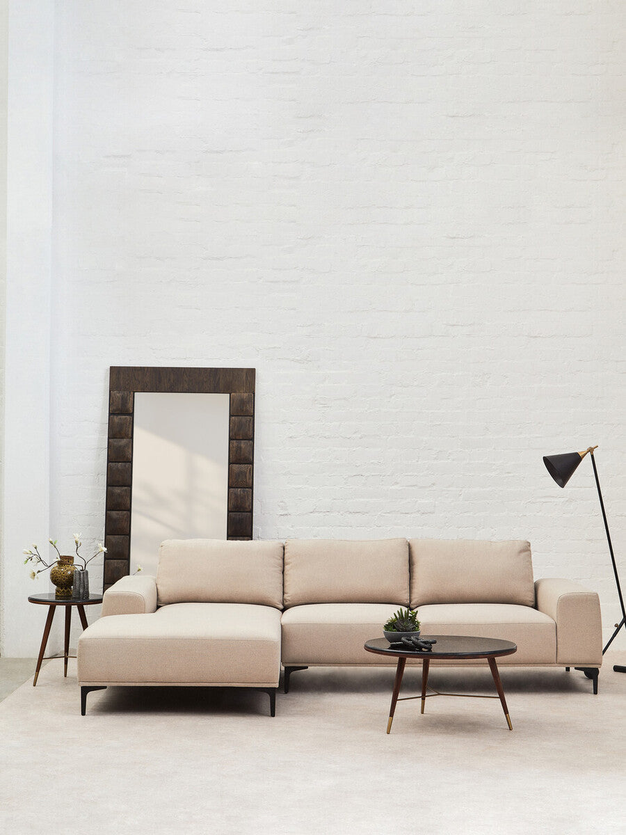 Beige sectional sofa in a modern living room with a mirror and lamp.
