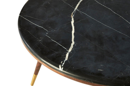 Round black marble table with gold legs on a white background