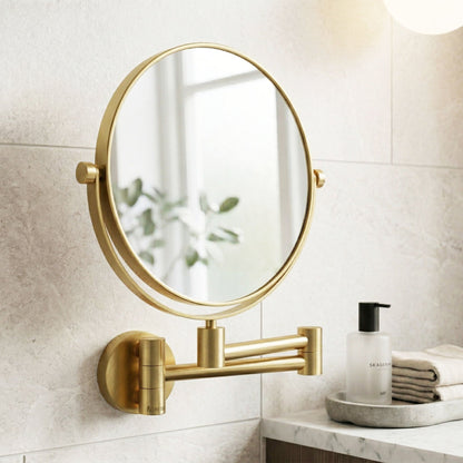Gold wall-mounted mirror in a bathroom setting with a white tiled wall and a small table with a bottle and towels.