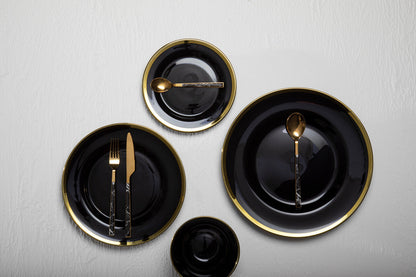 Four black glass charger plates styled across a dining table