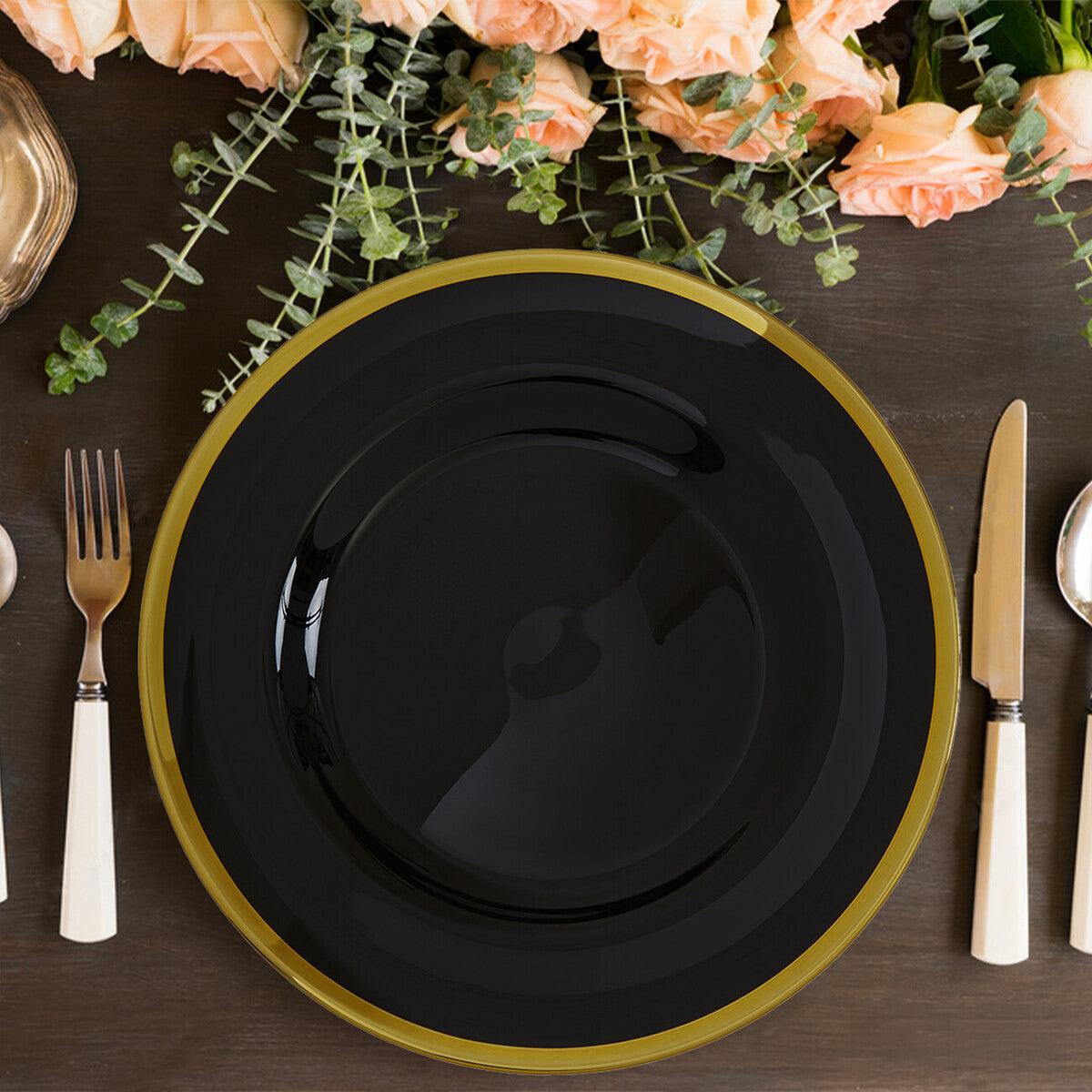 Black glass charger plate laid beneath a dinner plate in a place setting
