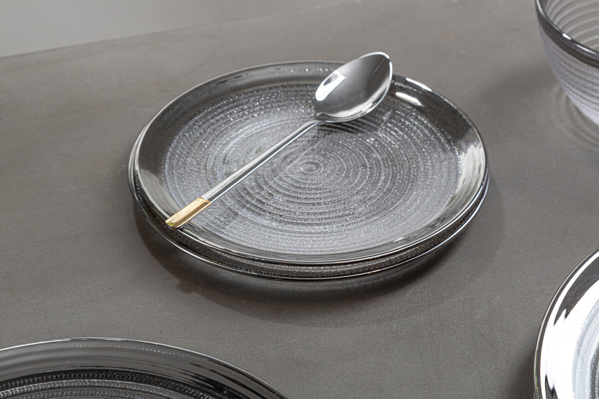 Glass charger plate laid beneath a dinner plate in a place setting