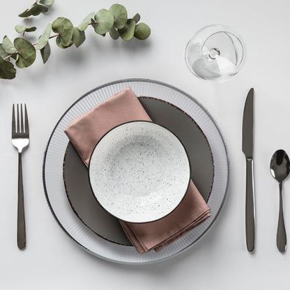 White glass charger plate laid beneath a dinner plate in a place setting