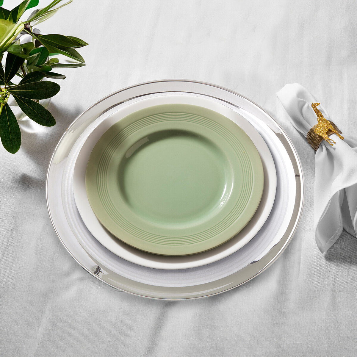 Four glass coupe charger plates styled across a dining table