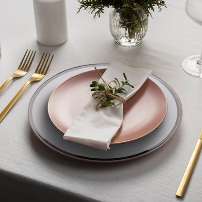 Glass charger plate laid beneath a dinner plate in a place setting