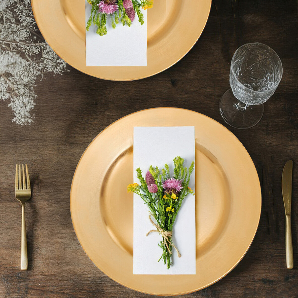 Gold charger plate styled with glassware and cutlery on a dining table
