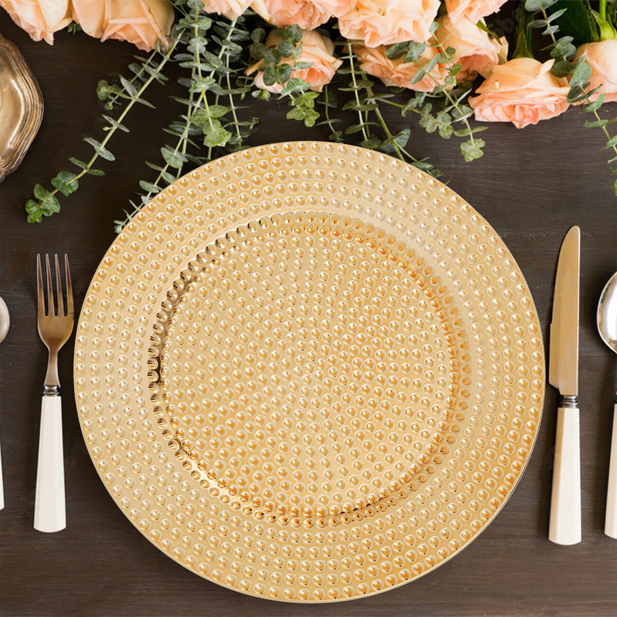 Four gold hammered charger plates styled across a dining table