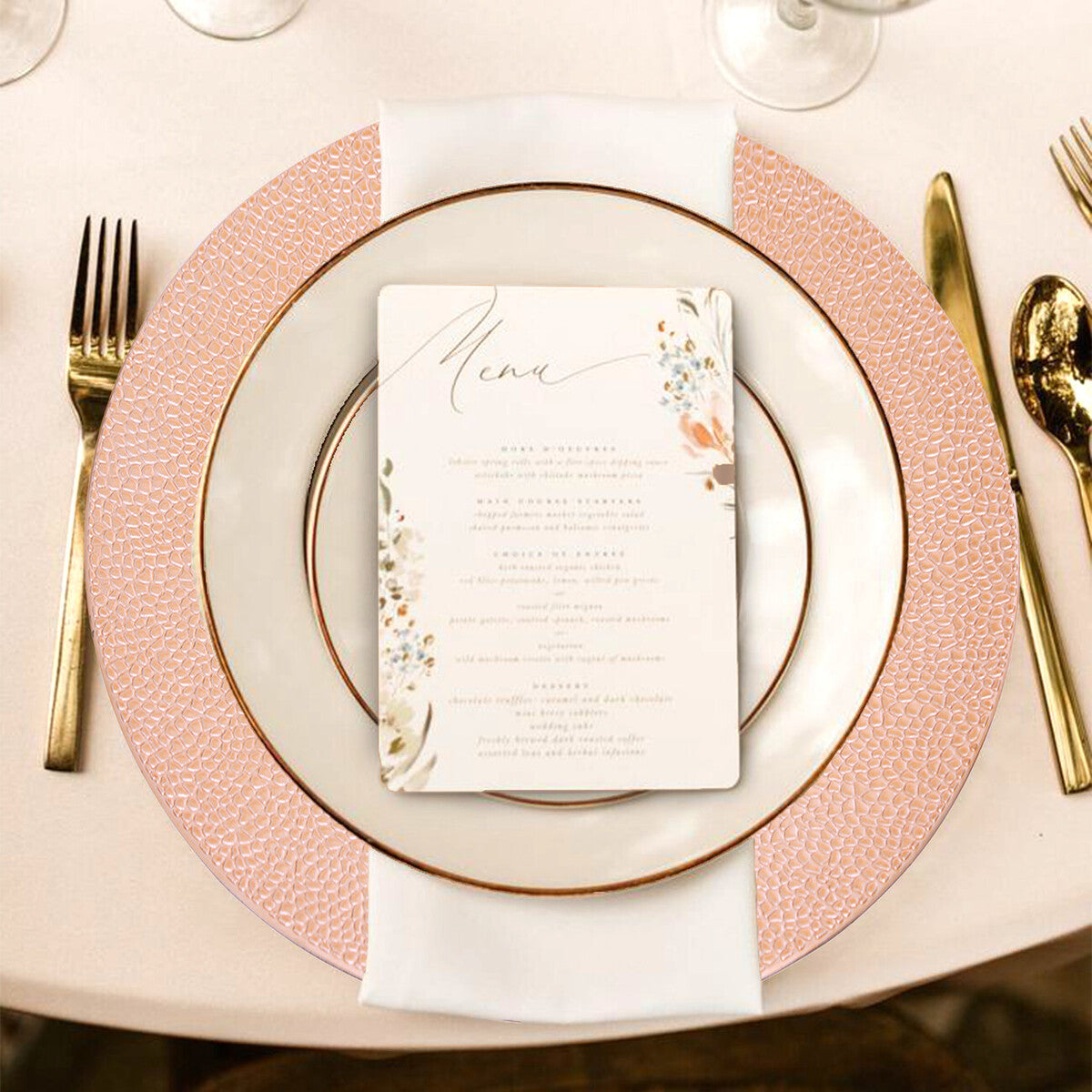 Four rose gold charger plates styled across a dining table