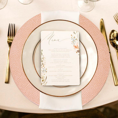 Four rose gold charger plates styled across a dining table