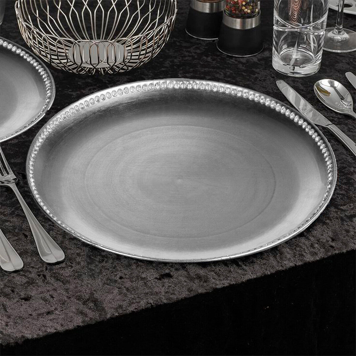 Four silver charger plates styled across a dining table