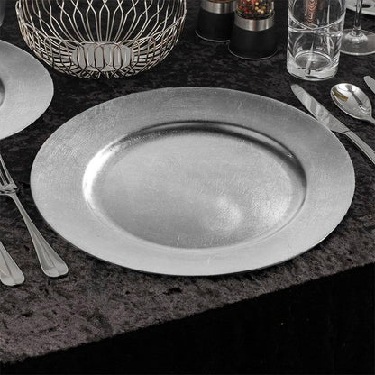 Four silver charger plates styled across a dining table