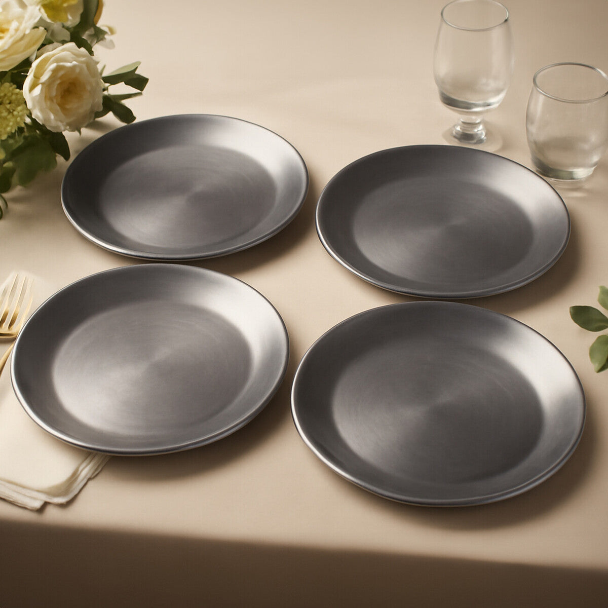 Four silver coupe charger plates styled across a dining table