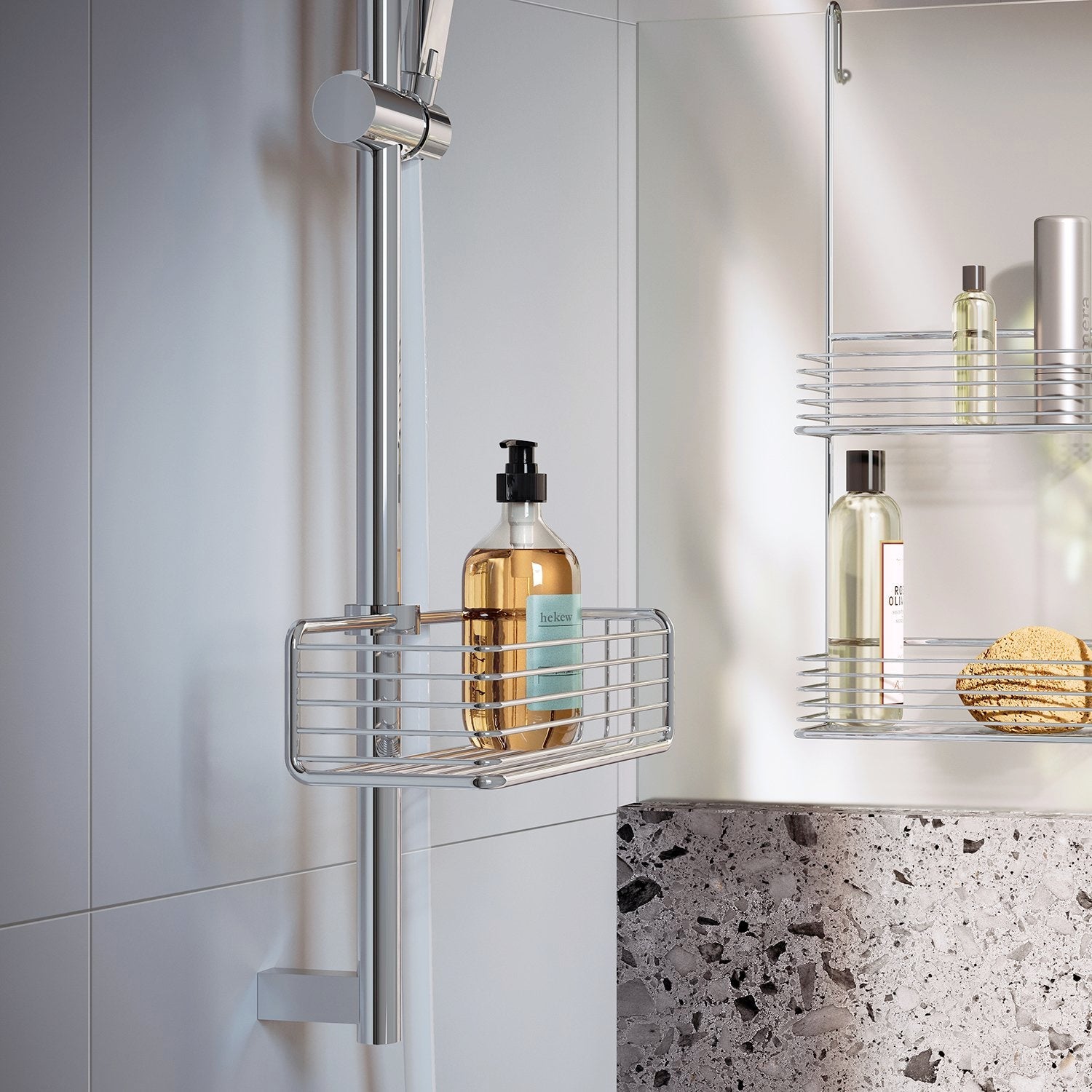 Smedbo Sideline DK1106 Chrome Riser Rail Basket in Use — Holding Amber Pump Bottle on Chrome Shower Rail, Mirror Reflection Showing Second Basket with Shower Oils and Natural Sponge, Terrazzo Bath Surround