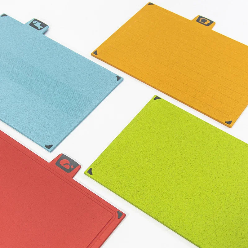 Four colourful cutting boards in blue, orange, red, and green on a white background