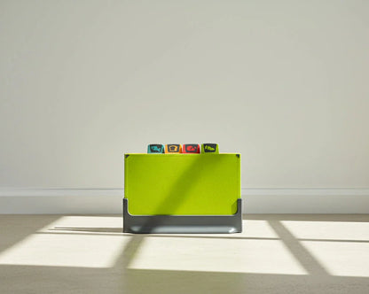 Green cutting board on a light grey surface and white wall background