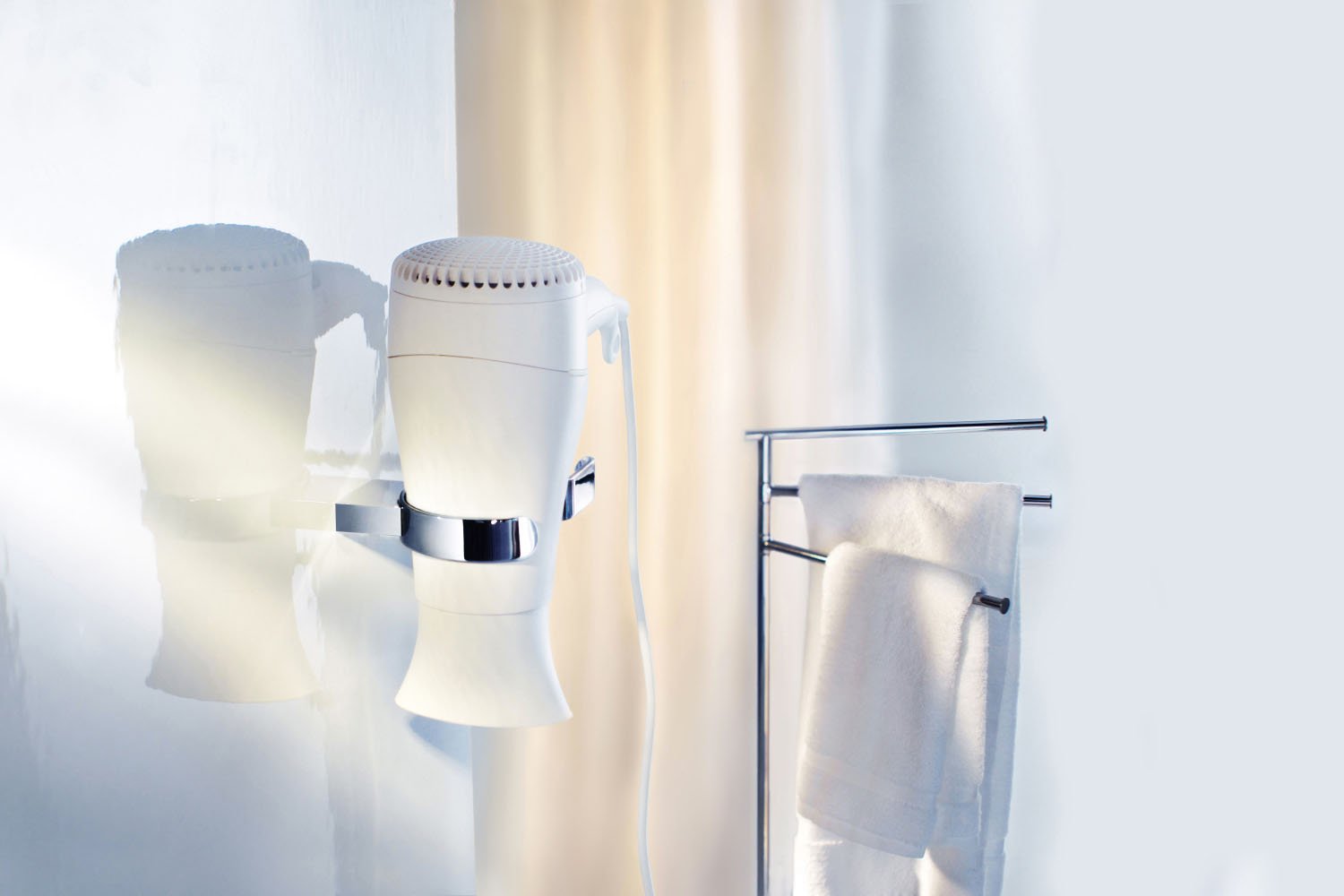 Wall-mounted hairdryer holder (AK323) with a towel rack holding a white towel in a bathroom setting.