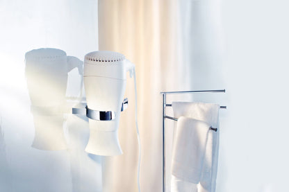 Wall-mounted hairdryer holder (AK323) with a towel rack holding a white towel in a bathroom setting.
