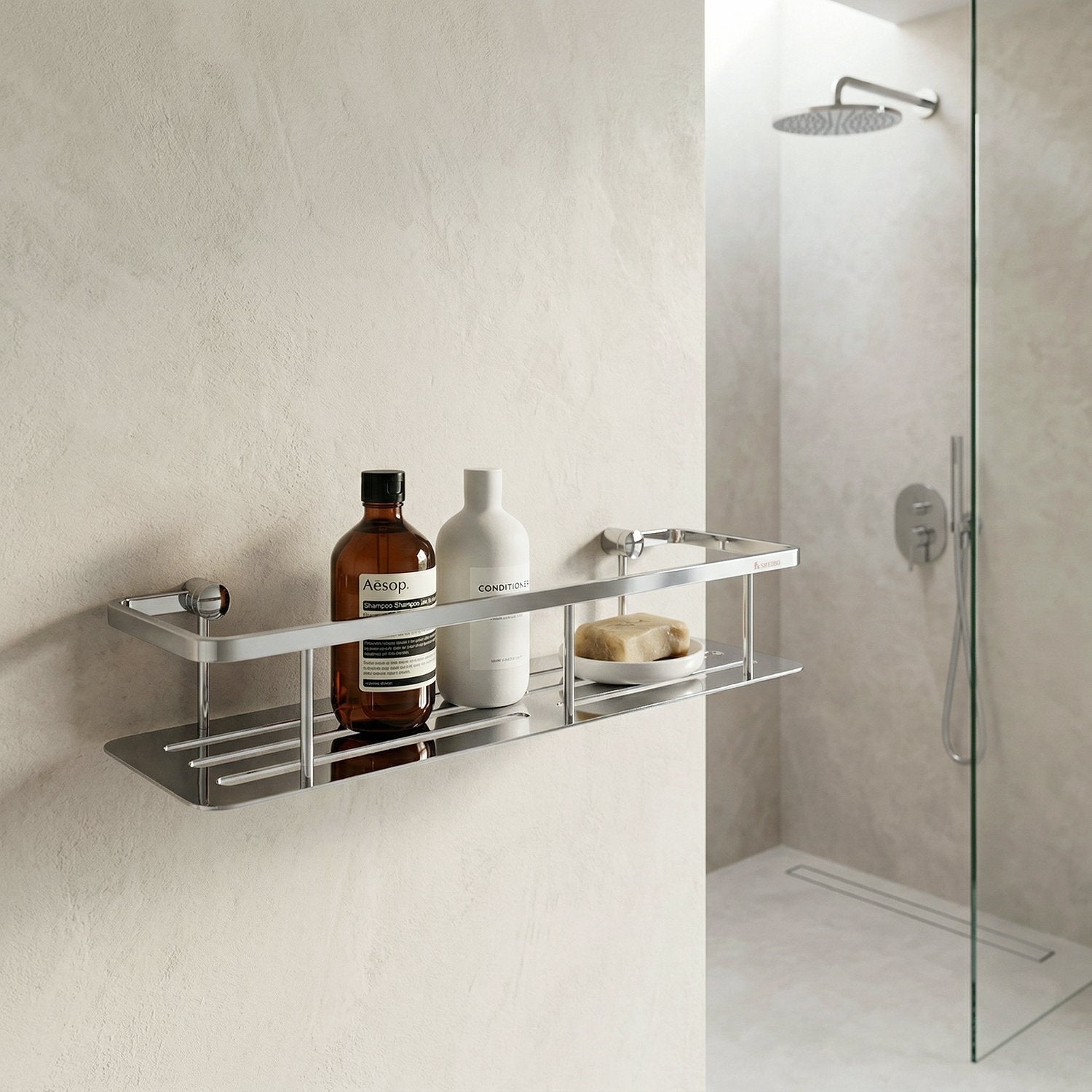 Smedbo Sideline DK3005 Wide Polished Chrome Shower Basket — Wall-Mounted on Textured Plaster Wall Beside Frameless Glass Shower, Styled with Aesop Shampoo, Conditioner and Soap Bar
