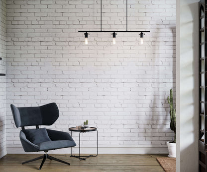Modern gray chair in a room with a white brick wall and pendant light.