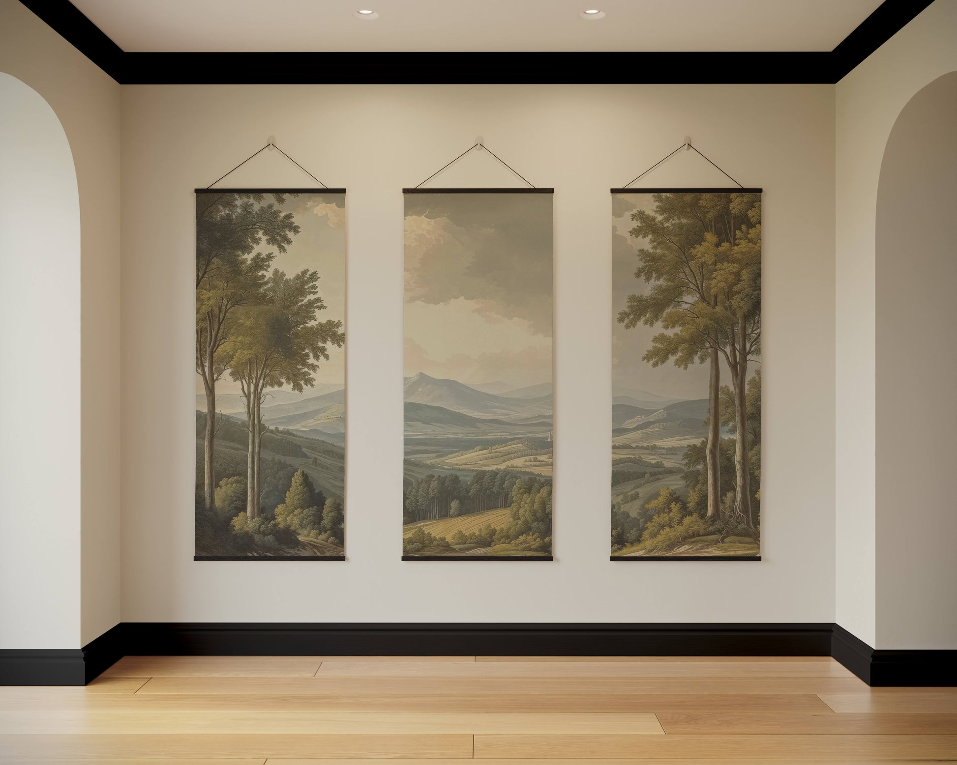 Three landscape paintings hanging on a wall in a room with wooden flooring.