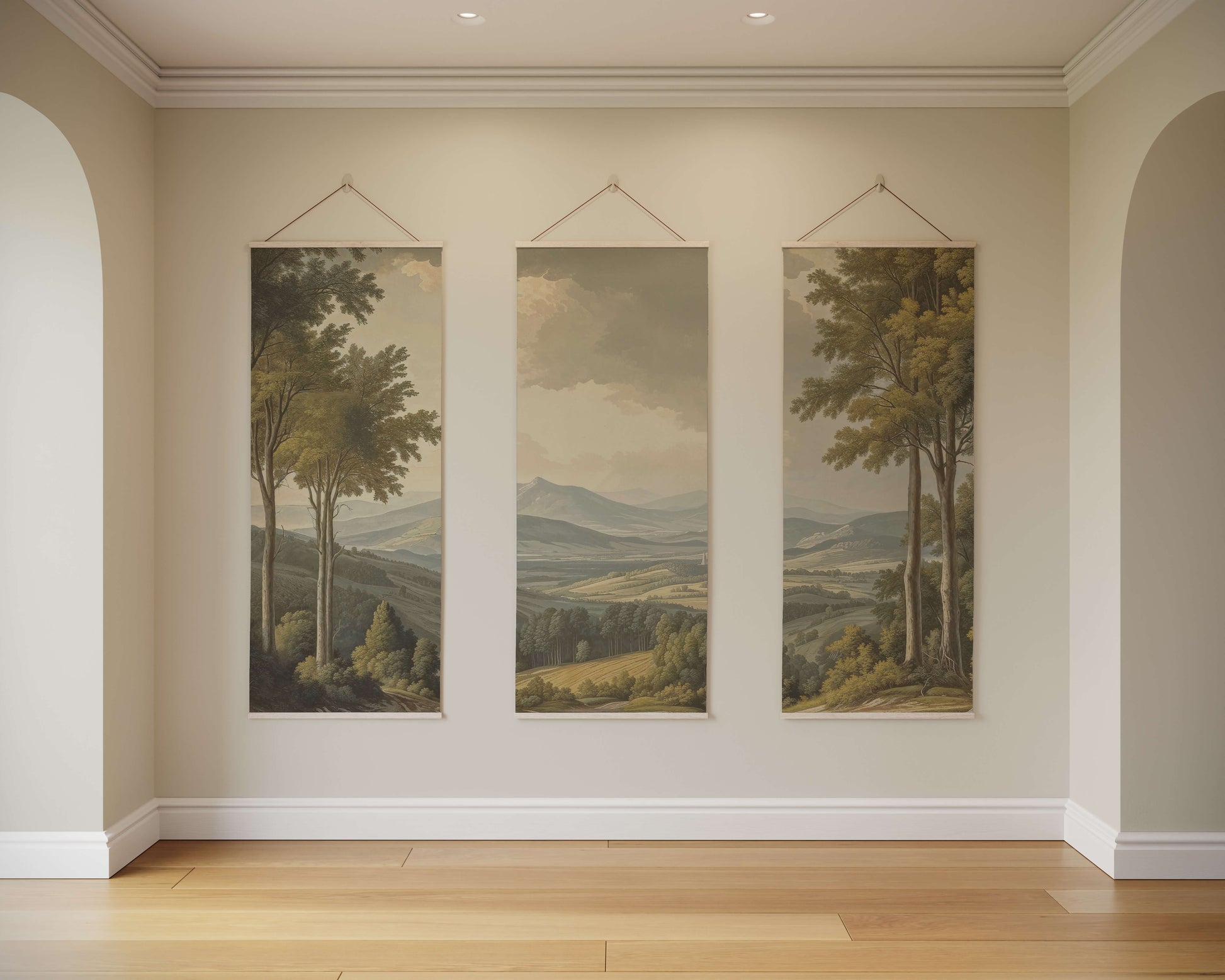 Three landscape paintings hanging on a wall in a room with wooden flooring.