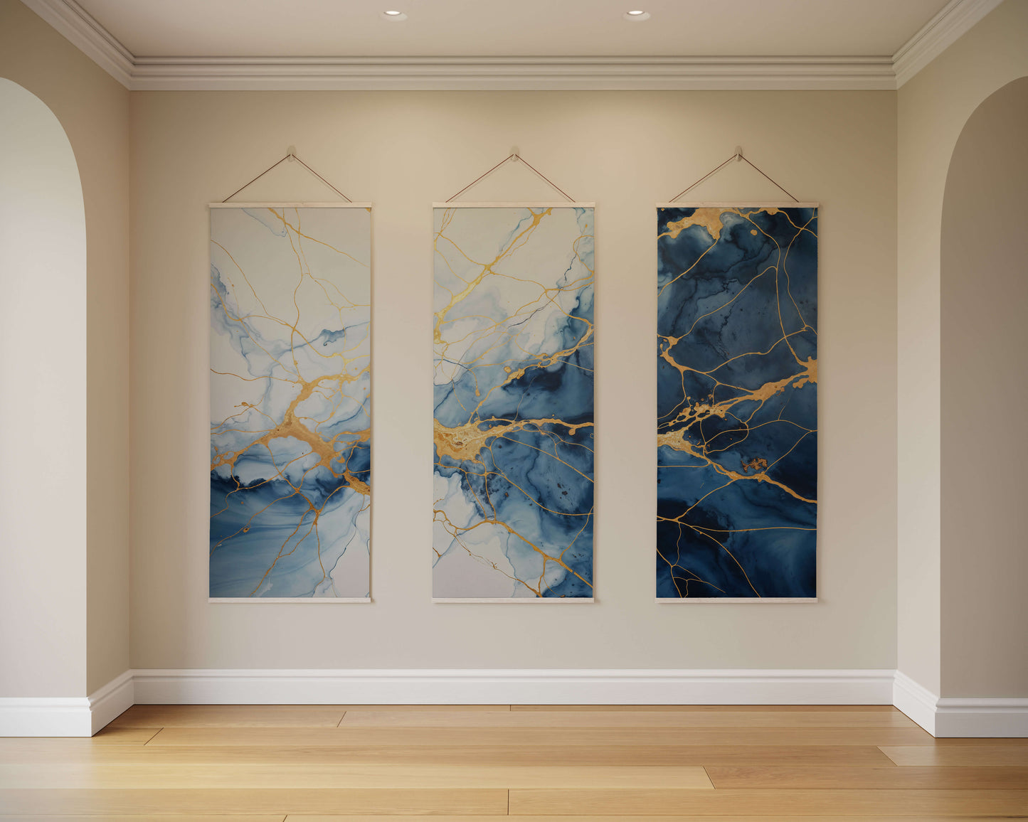 Three abstract wall hangings with blue and gold patterns on a beige wall.