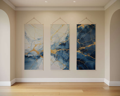 Three abstract wall hangings with blue and gold patterns on a beige wall.
