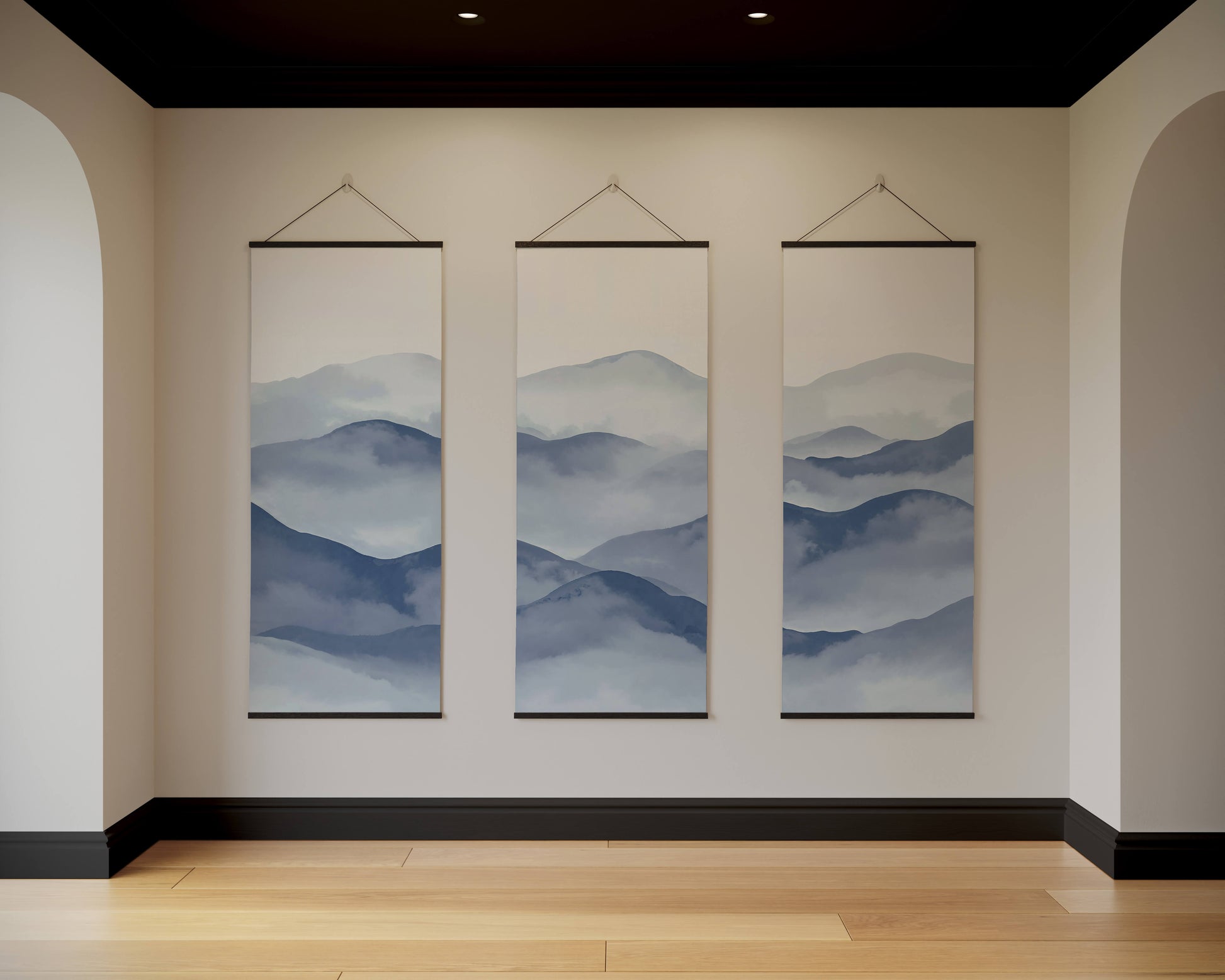 Three hanging wall art pieces depicting mountain landscapes in a room with beige walls and wooden flooring.
