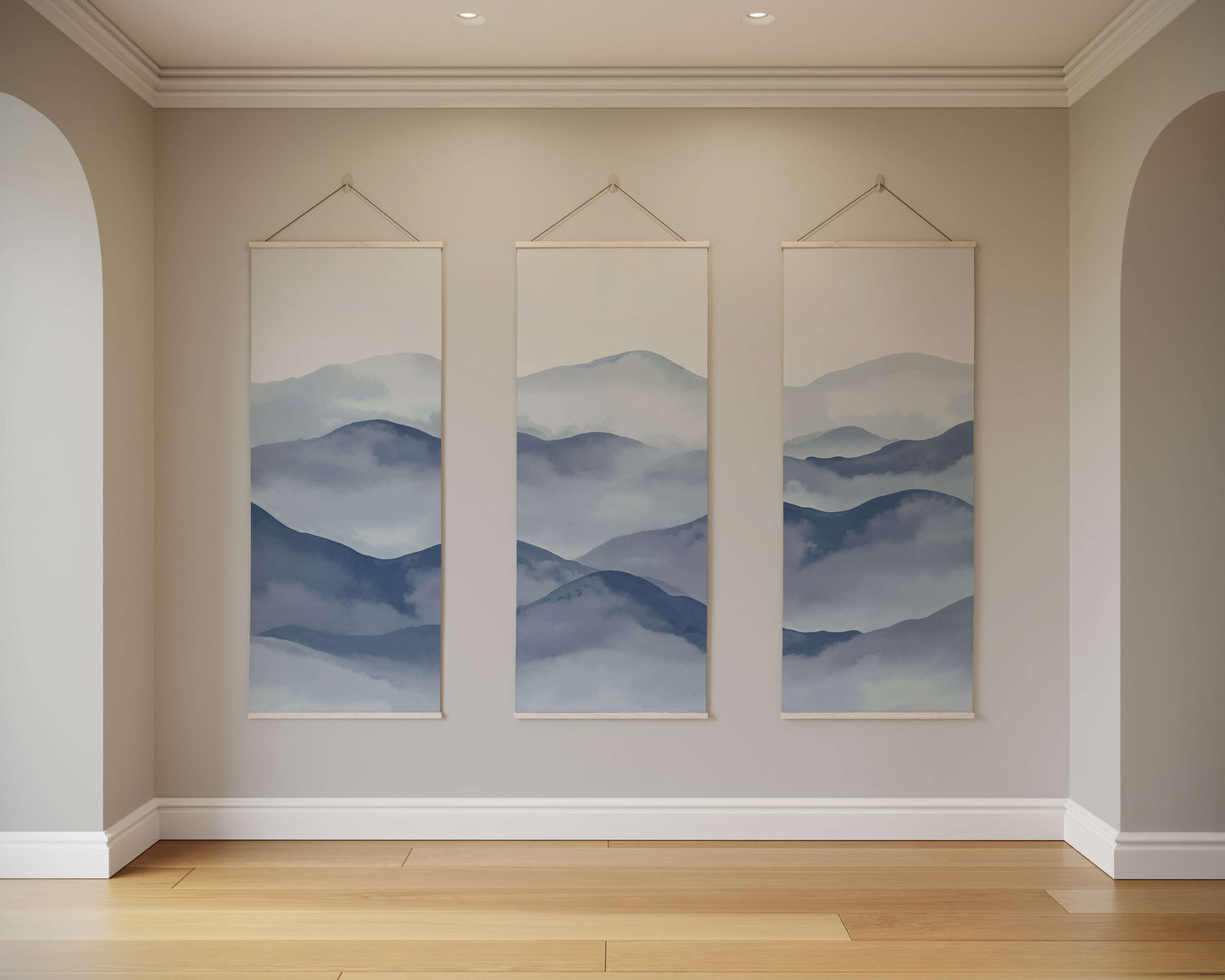 Three framed landscape paintings of mountains on a beige wall.